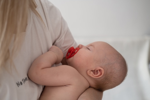 眠っている小さな男の子は母親の手に直面しています。母性の概念。乳首。幸せな家族。永遠の愛。授乳中のお母さん。小さな息子と一緒にリラックス。家に。愛。甘い。優しさ。高品質の写真