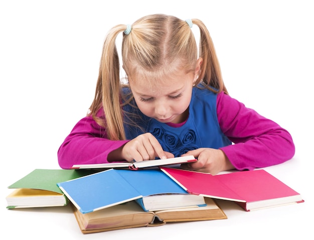 Little smart girl holding a book and reading it, on a white background