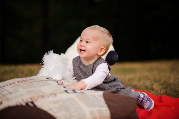 Piccola neonata sorridente che si siede su una coperta nel parco