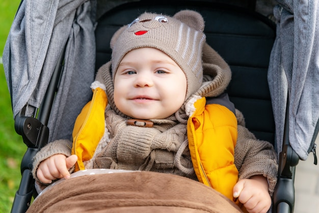 Little smiling baby in stroller close up portrait of cute toddler boy covered with a blanket