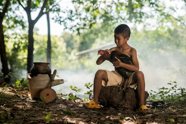 Photo little smiling boy and cock on green forest in countryside