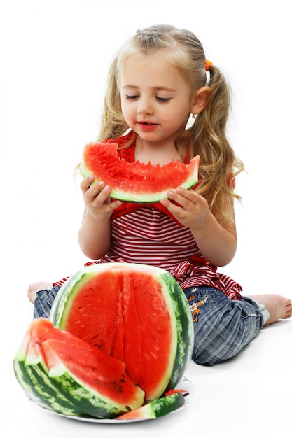 La piccola ragazza sorridente mangia un'anguria