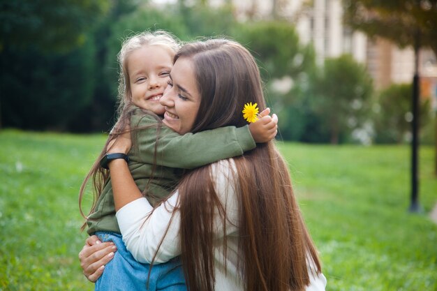 Foto piccola ragazza sorridente che abbraccia sua madre nel parco