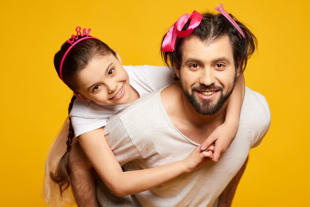 Little Smiling Girl Is Riding on Fathers Back.