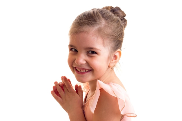 Little smiling girl in pink ballet dress with bundle on white background in studio