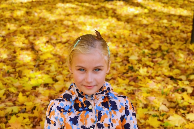 Little smiling girl with bright autumn leaves on a background