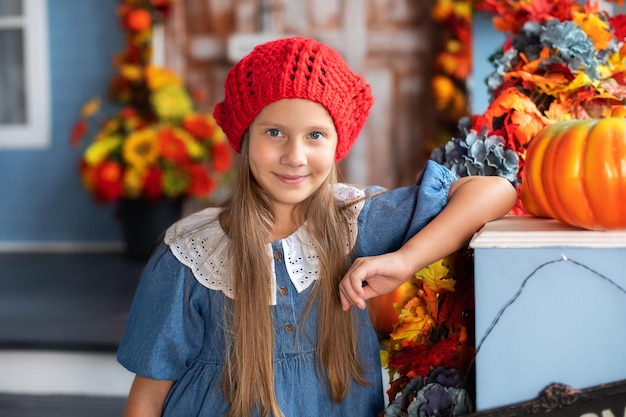 ハロウィーンの家のポーチにカボチャと少し笑顔の幸せな女の子スタンド。