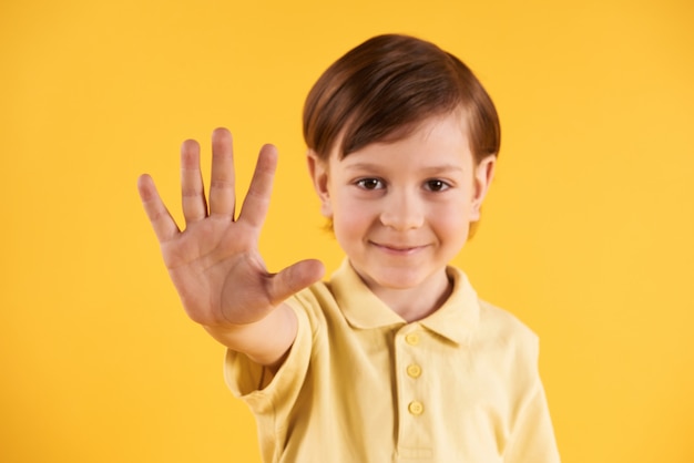 Little smilling boy shows palm of hand.