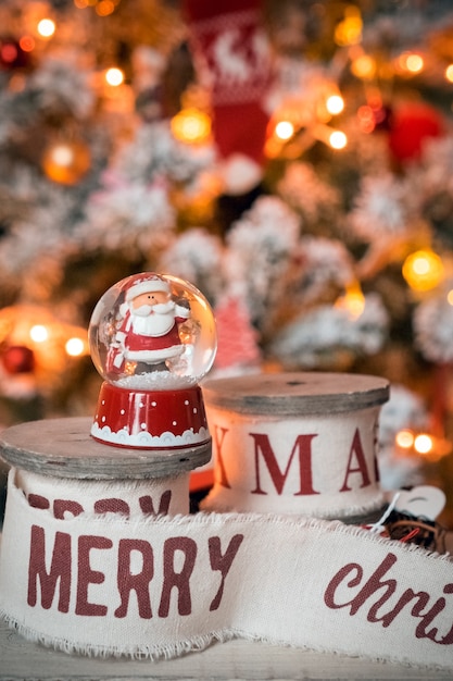 Piccola palla di neve con babbo natale sullo sfondo dell'albero di natale