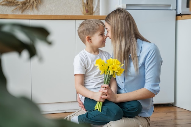 Photo a little son gives flowers to his mother the boy congratulates his mother on march 8