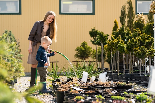 写真 幼い息子は、お母さんが園芸用品センターの植木鉢に水をやるのを手伝います