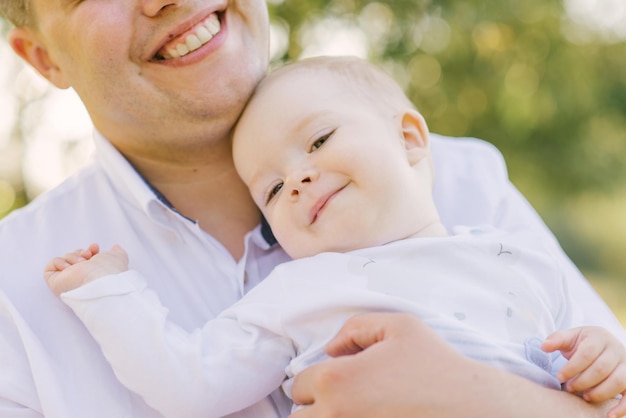 The little son in his father's arms is smiling and happy