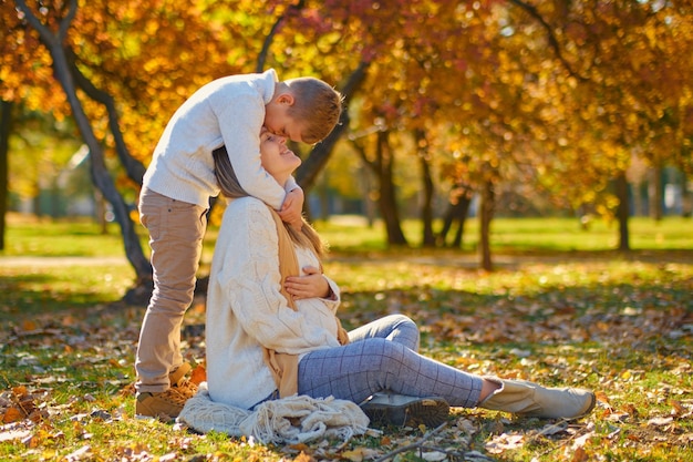 Little son hugs his pregnant mom on the nature