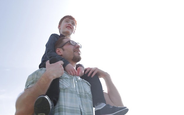 Photo little son sits on his father's shoulders