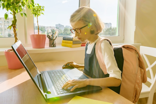 Little student girl of 8 years old uses laptop