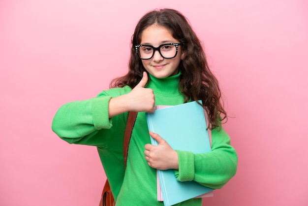 Little student girl isolated on pink background with thumbs up because something good has happened