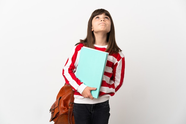 Little student girl isolated on white wall and looking up