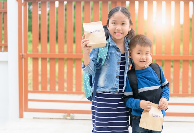 Piccoli studenti che tengono la borsa del pranzo prima di andare a scuola