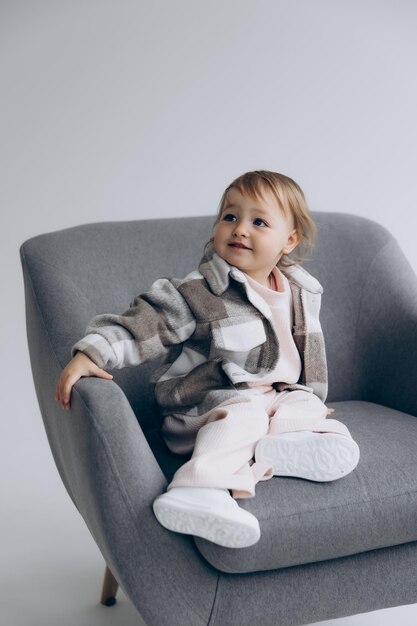 маленькая стильная девочка полутора лет позирует для фото на белой студийной циклораме