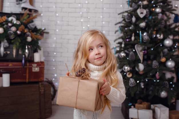 Little stylish girl posing near the New Year tree in anticipation of Christmas