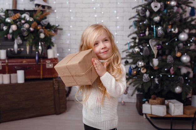 Little stylish girl posing near the New Year tree in anticipation of Christmas.