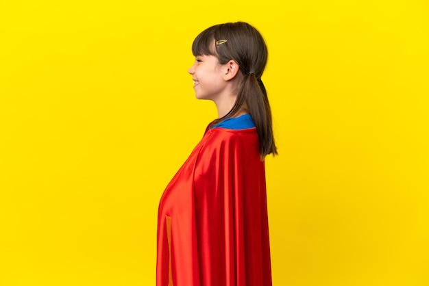 Little super hero kid isolated on purple background in lateral position