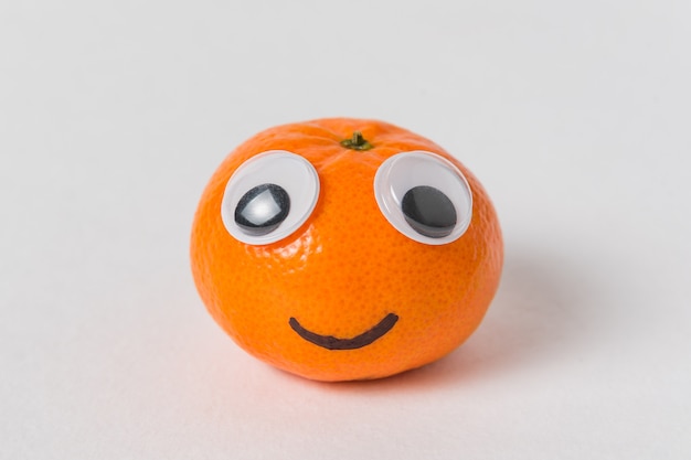 Photo little tangerine with big eyes and smile. mandarin character on white