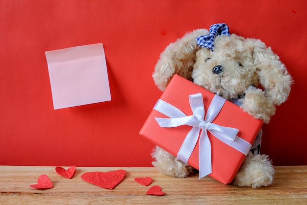 Photo little teddy bear with gift on red background