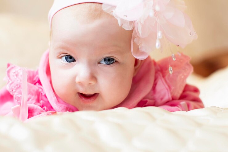 Little three month old girl with blue eyes in pink pay.