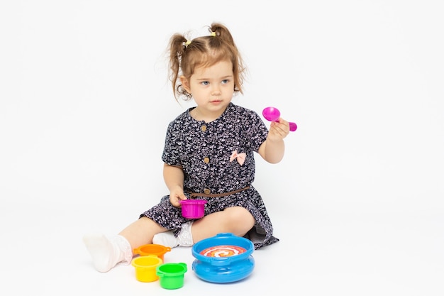 Little toddler 2 years old playing kitchen toy on white background