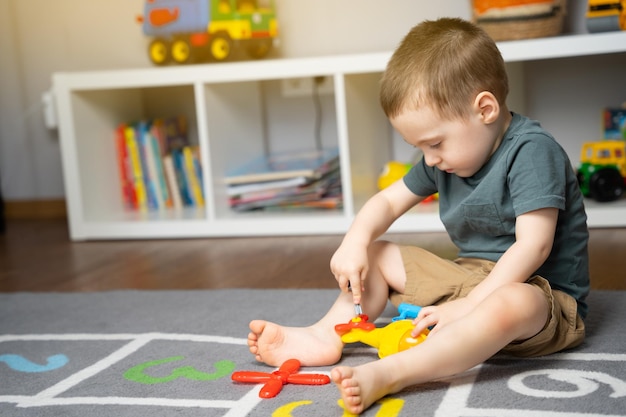 Photo a little toddler boy 25 years is playing with a toy helicopter assembling and disassembling it educational toys for kids children's room in home indoors