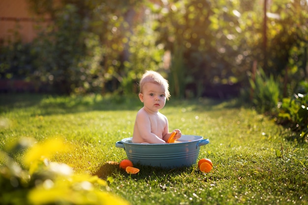 Little toddler boy bathes in the park with oranges