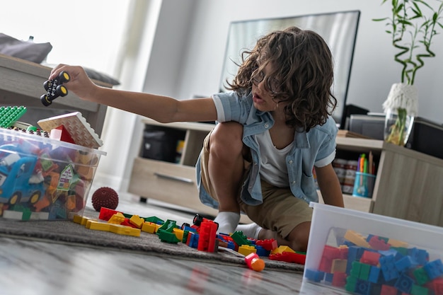 Little toddler boy playing with colorful plastic blocks at home building creative game imagination