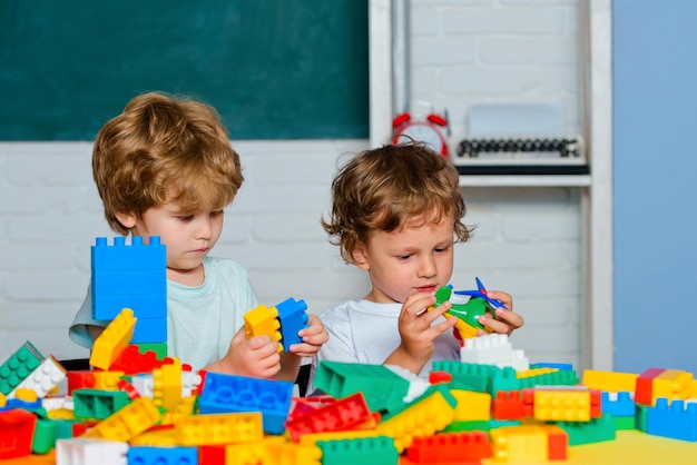 子供のための子供部屋の教育ゲームでおもちゃの建設業者のおもちゃの混乱で遊んでいる小さな幼児の男の子