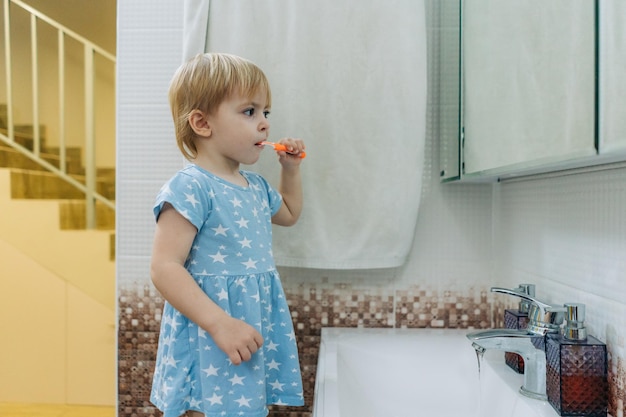 Little toddler girl brushes her teeth in the bathroom