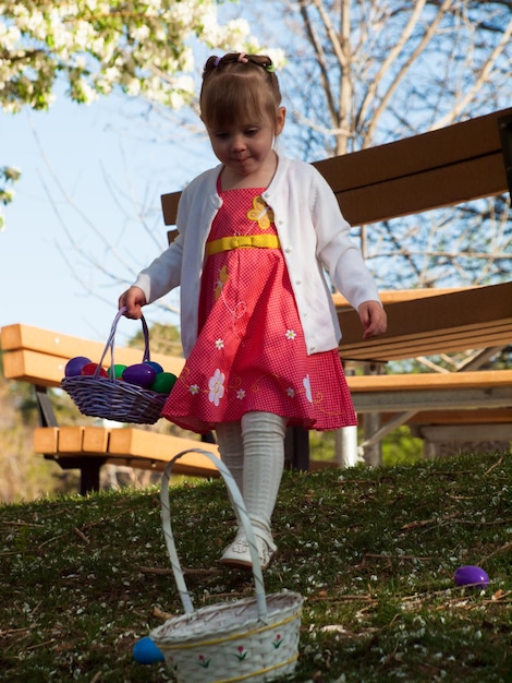 Little toddler girl on Easter egg hunt in urban park.