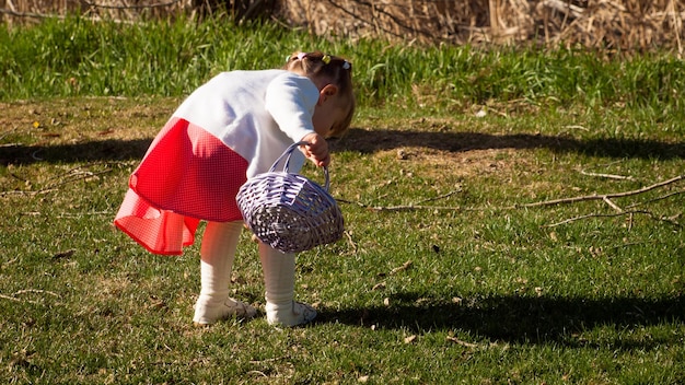 Bambina bambino sulla caccia alle uova di pasqua nel parco urbano.