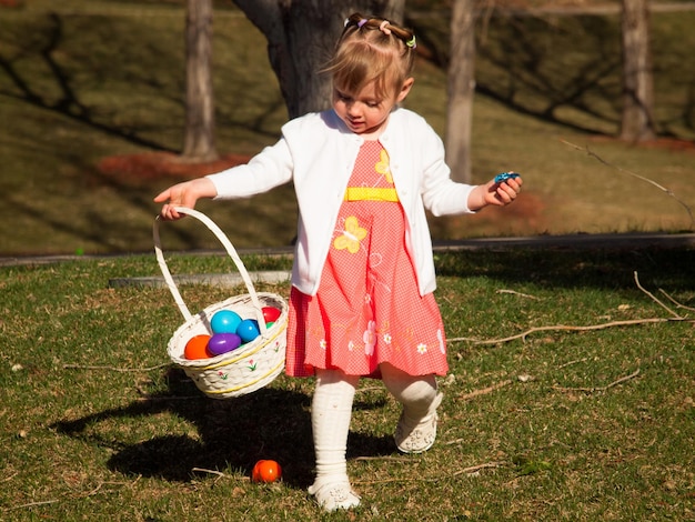 Little toddler girl on Easter egg hunt in urban park.