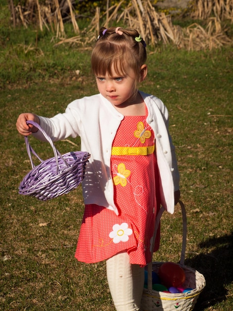 Little toddler girl on Easter egg hunt in urban park.