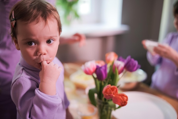 Little toddler girl licking her finger while cooking with family