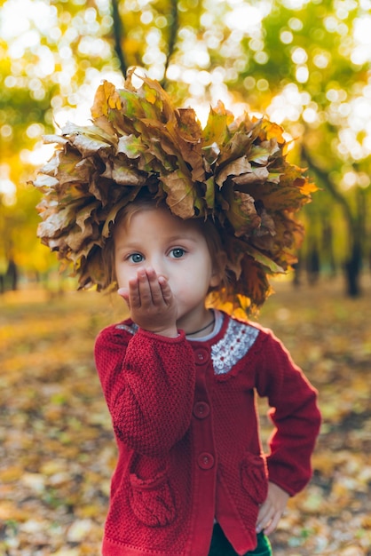 Little toddler girl playing with maple leaves wreath