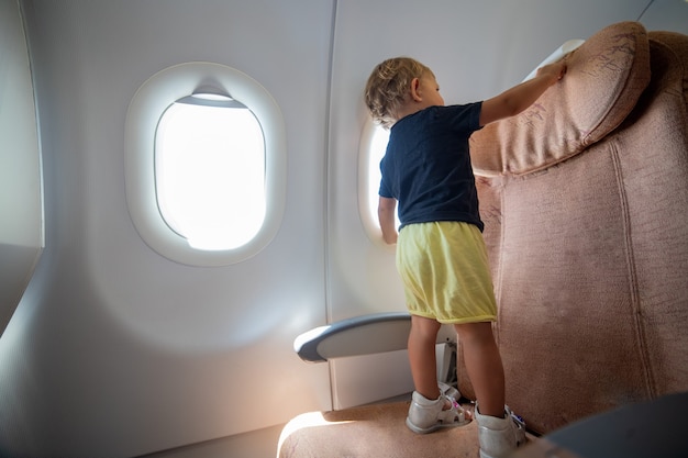 Little toddler on the plane stands on the passenger seat dangerous