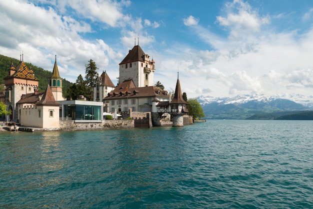 Little tower of Oberhofen castle in the Thun lake with mountains on background in Switzerland