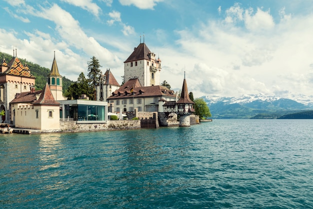 Little tower of Oberhofen castle in the Thun lake with mountains on background in Switzerland