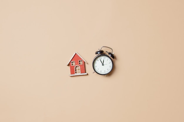 Little toy house and alarm clock on stark white background. Above view