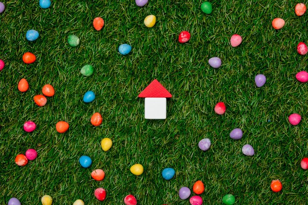 Little toy house and Easter candies around on green grass