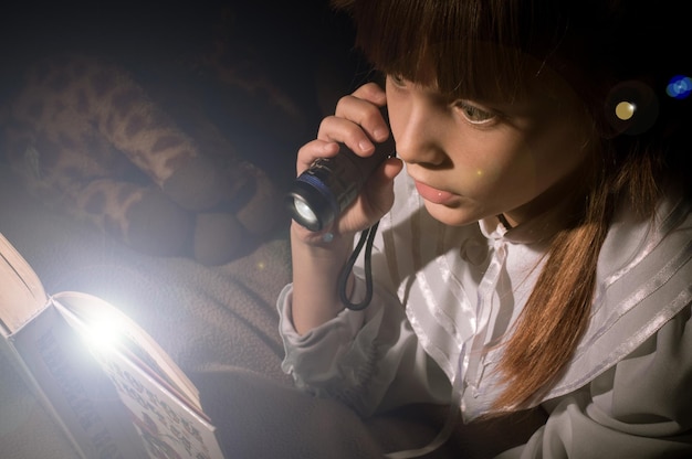 Little Ukrainian girl reads a book in the dark