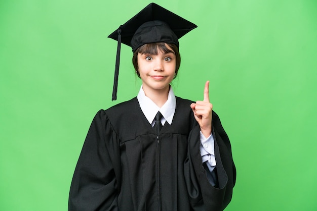 Piccola ragazza universitaria su sfondo isolato che punta con il dito indice una grande idea