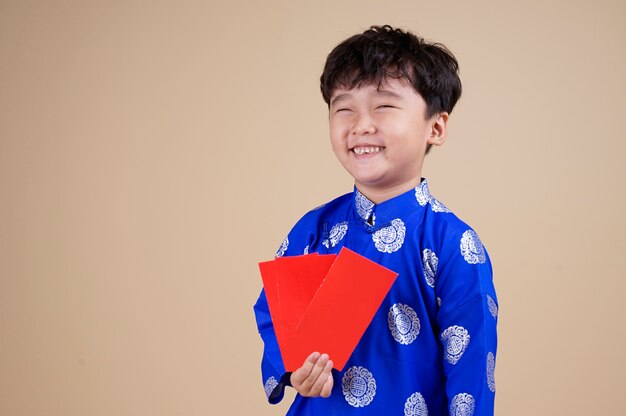 Photo little vietnamese boy holding red envelops for tet.