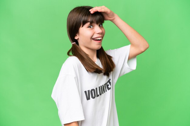 Little volunteer girl over isolated background doing surprise gesture while looking to the side
